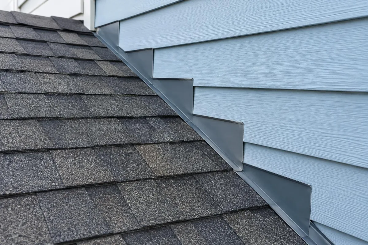 Shingles meeting a wall with metal trim at the joint.